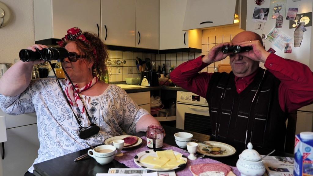 Foto: Zwei Personen sitzen mit Ferngläsern in der Hand am Frühstückstisch
