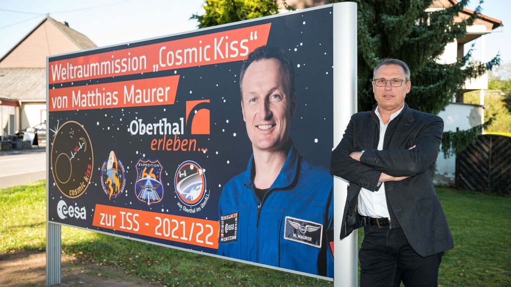 Der Oberthaler Bürgermeister Stephan Rausch neben einem Plakat zur Weltraummission von Matthias Maurer (Foto: picture alliance/dpa | Oliver Dietze)