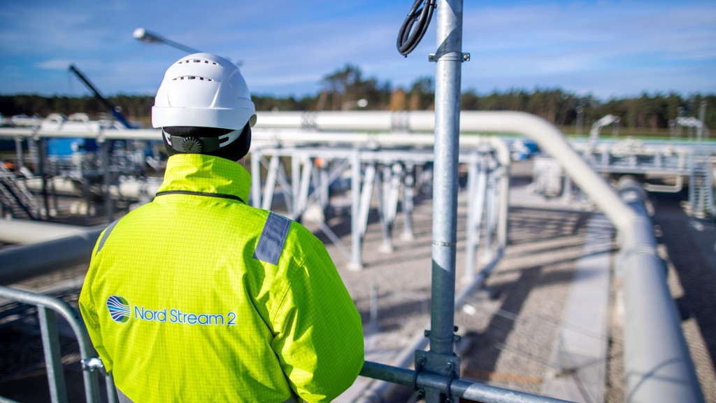 Ein Mann in Schutzkleidung steht vor einer Gaspipeline