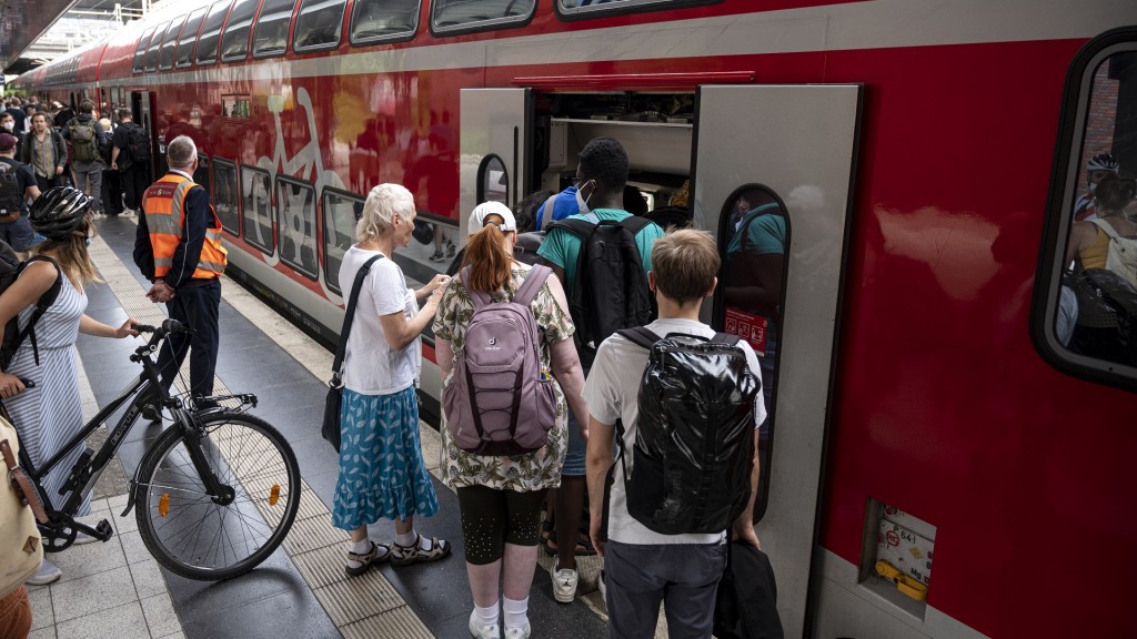 Mehrere Fahrgäste steigen am Bahnhof in einen Regionalexpress