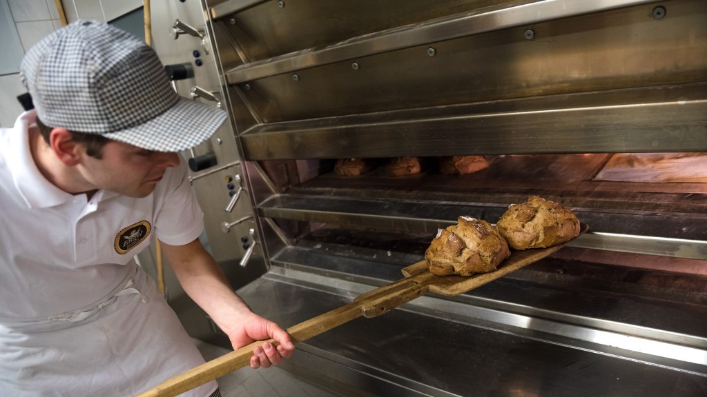 Ein Bäckermeister schiebt einen Laib Brot in den Ofen