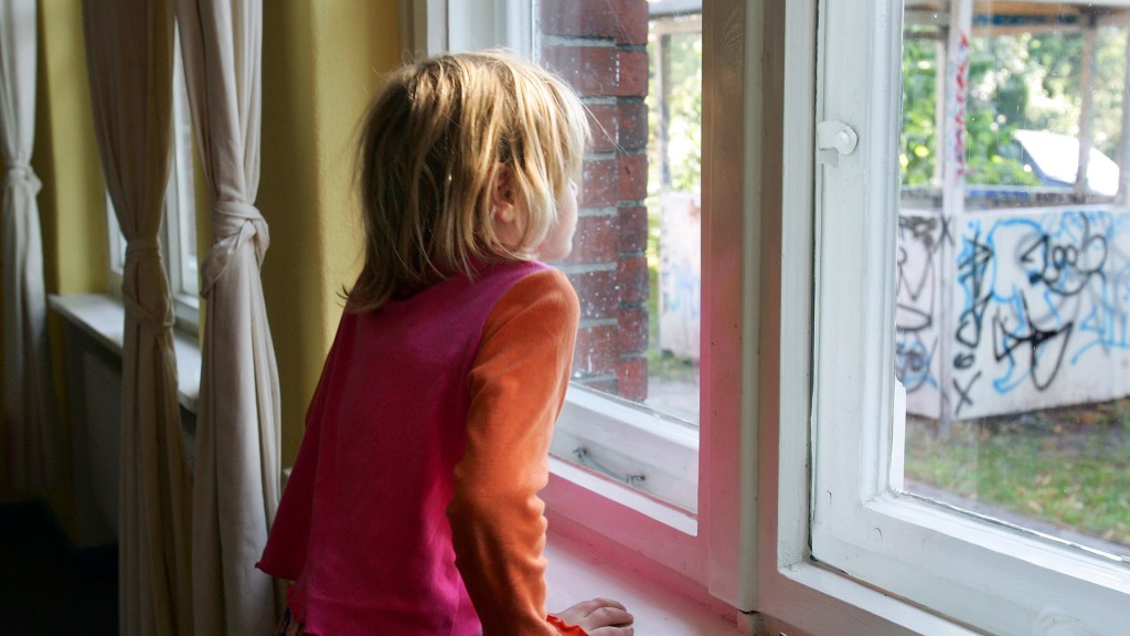 Kleines Mädchen schaut aus dem Fenster auf einen herunter gekommenen Spielplatz