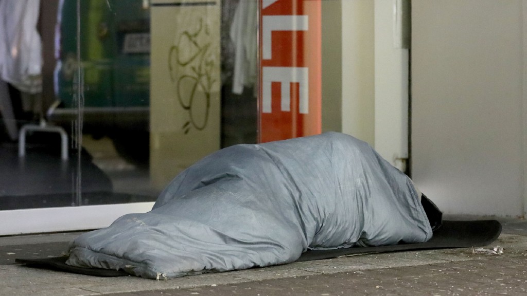Ein Obdachloser schläft vor einem Geschäft. 