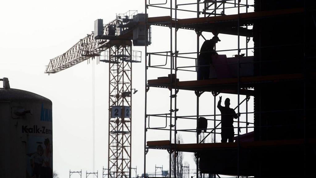 Bauarbeiter stehen auf einem Gerüst am Neubau eines Mehrfamilienhauses