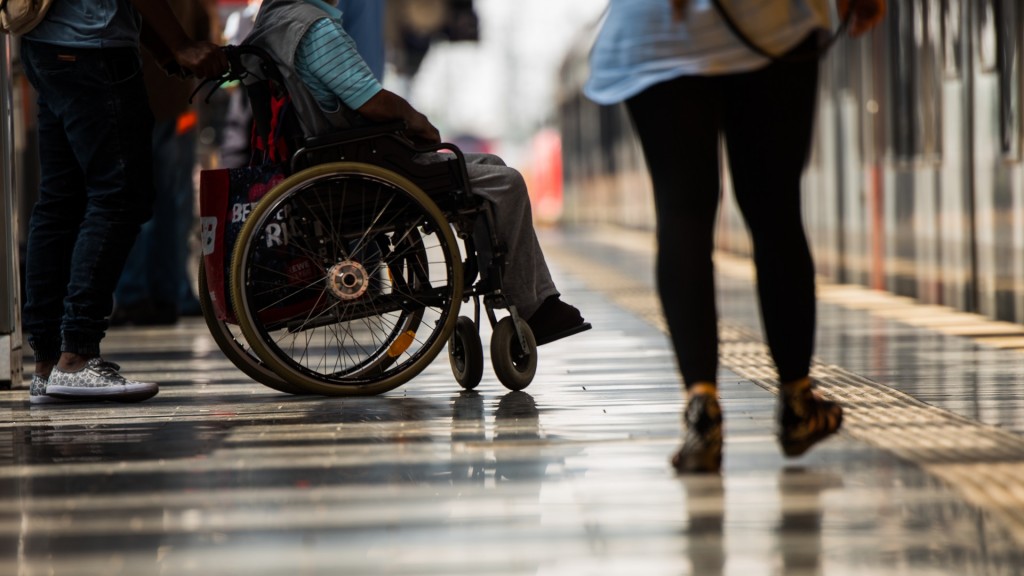 Ein Rollstuhlfahrer steht auf dem Bahnsteig