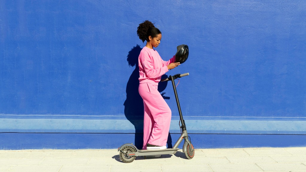 Foto: Eine Frau mit Helm auf einem e-Scooter