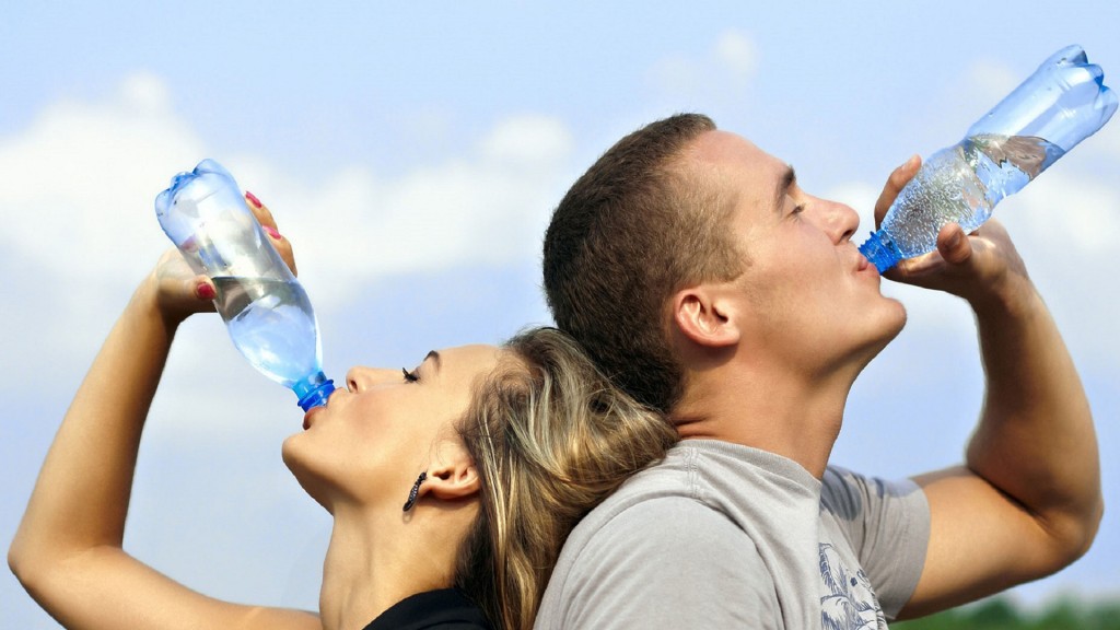 Eine Frau und ein Mann trinken jeweils Wasser aus einer Flasche