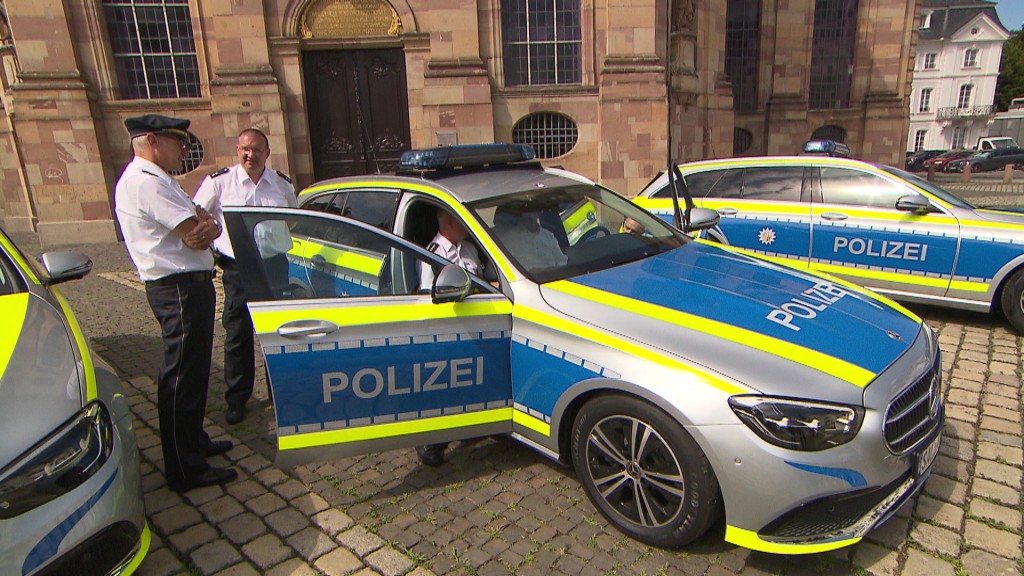 Polizisten stehen neben mehreren Polizeifahrzeugen