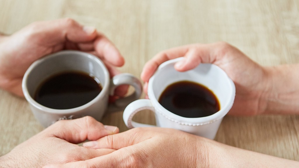 Hände berühren sich beim Kaffee trinken als Zeichen für Trost und Anteilnahme.