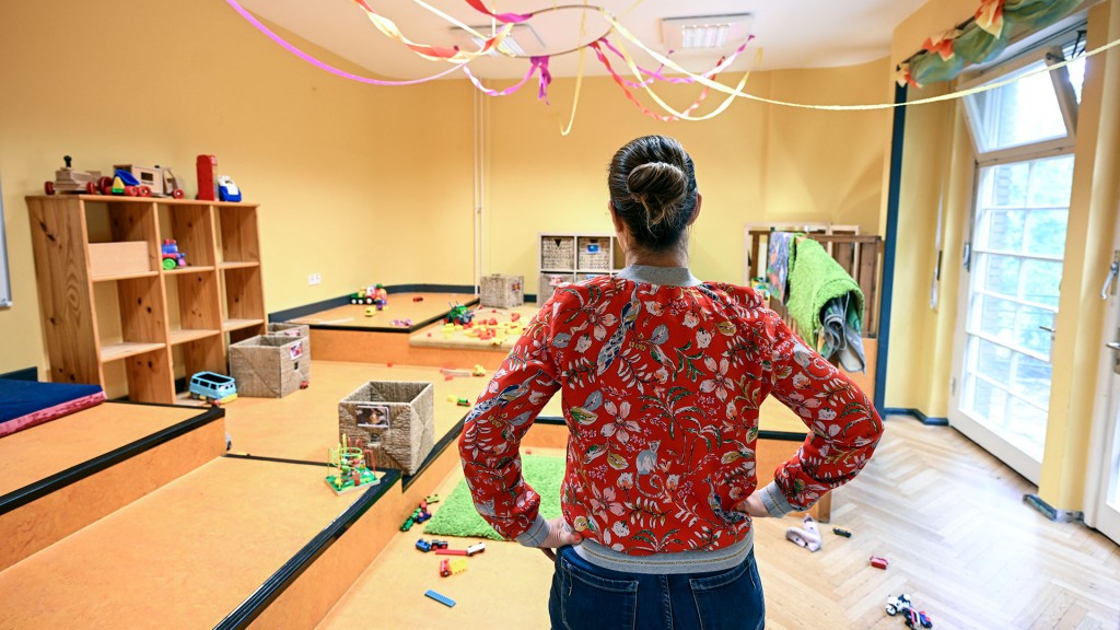 Eine Betreuerin steht alleine im leeren Raum einer Kindertagesstätte