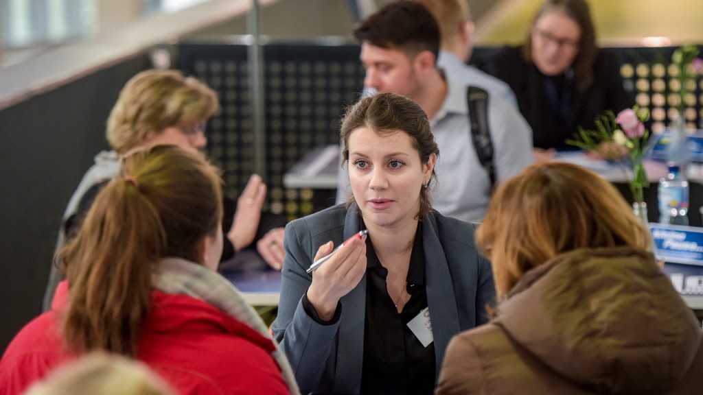 Besucher einer Jobmesse an einem Stand in einem Beratungsgespräch