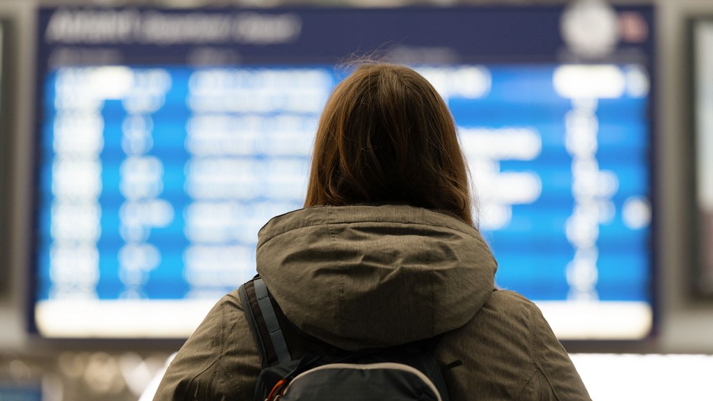 Eine Frau steht im Bahnhof vor einer Anzeigetafel