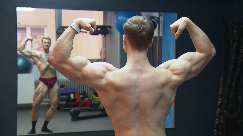 Foto: Leo (22) posiert im Fitnessstudio vor einem Spiegel so, wie es für Bodybuilder üblich ist.