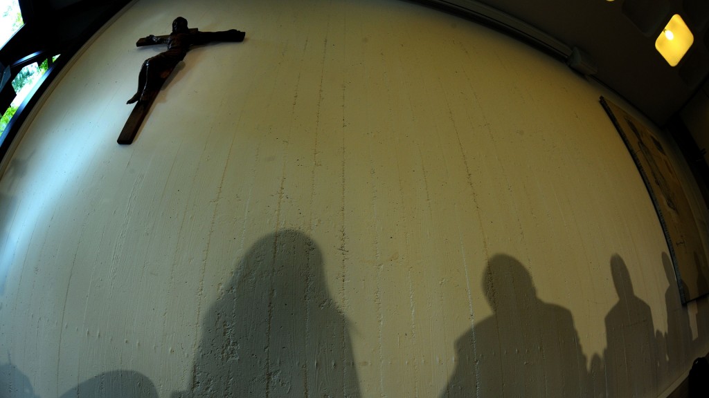 Kreuz in einer Kirche mit den Schatten von Personen an einer Wand