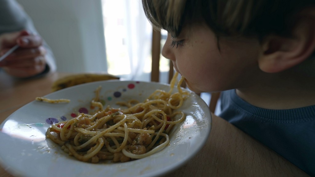 Ein Kind isst Spaghetti von einem Teller
