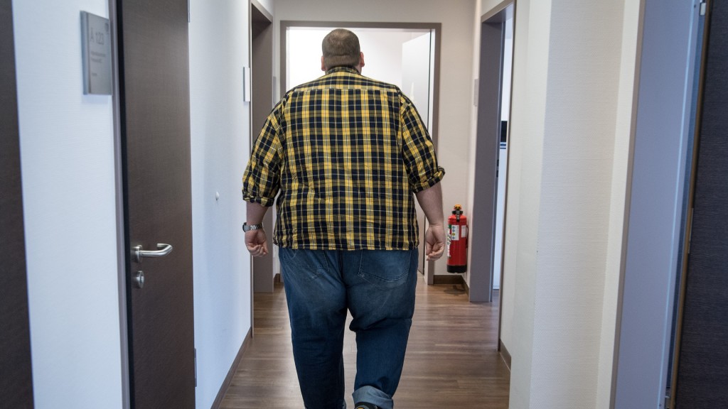 Ein Mann mit Übergewicht geht einen Flur entlang
