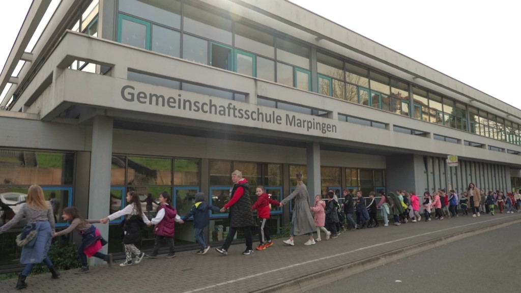 Foto: Menschen halten sich an den Händen vor der Gemeinschaftsschule Marpingen