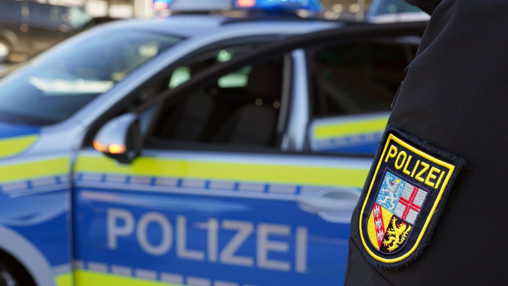 Bildmontage: Ein saarländischer Polizist steht vor einem Einsatzfahrzeug