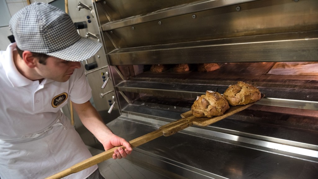 Foto: Ein Bäckermeister schiebt einen Laib Brot in den Ofen