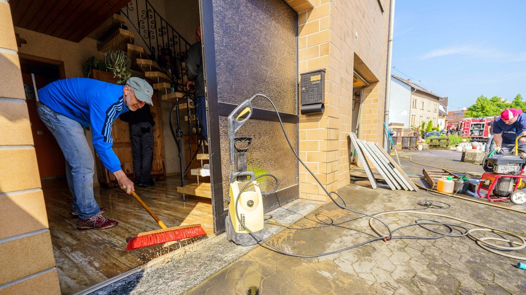 Ein Anwohner kehrt das Wasser aus der vom Hochwasser betroffenen Erdgeschoss-Wohnung in Kleinblittersdorf