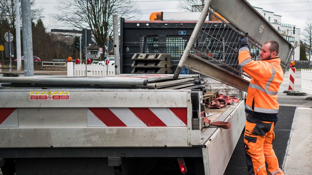 Personal der Straßensicherung hantiert mit Absperrbarken an der Ladefläche eines LKW