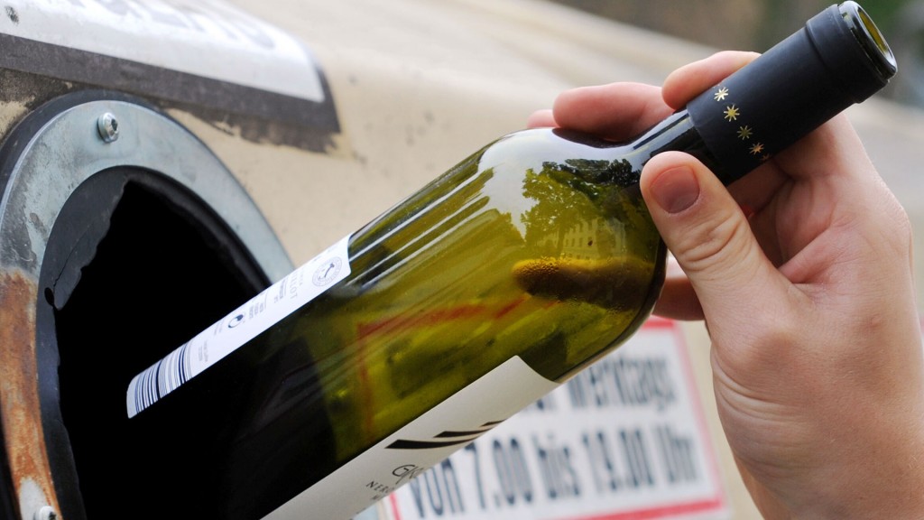Foto: Jemand wirft eine leere Flasche in einen Altglascontainer