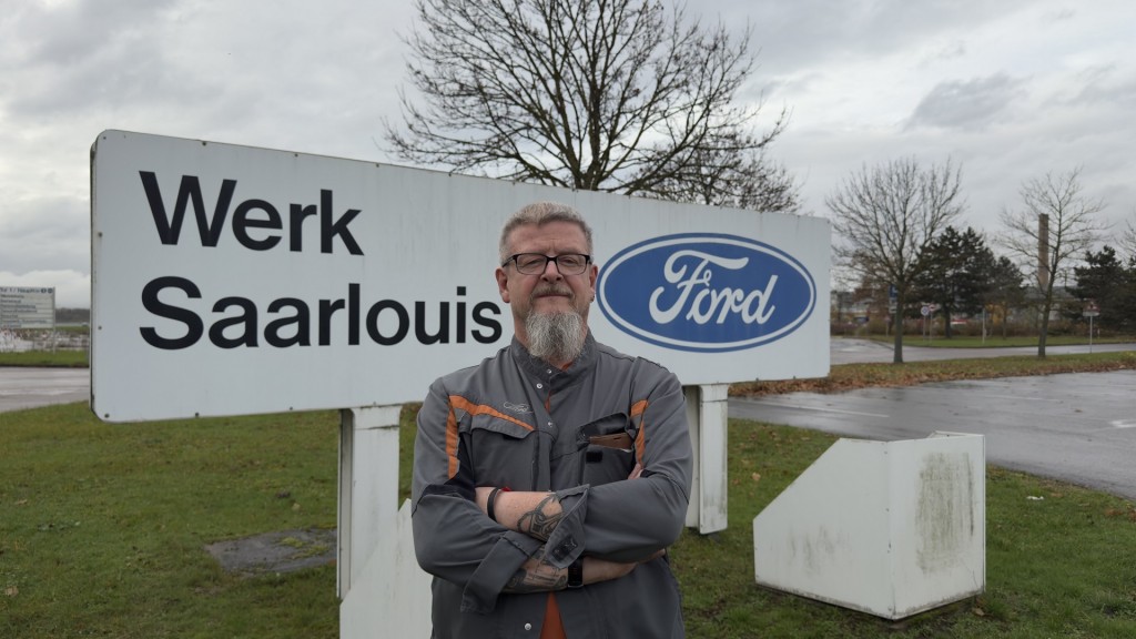 Michael Peters. Im Hintergrund das Schild des Fordwerkes Saarlouis