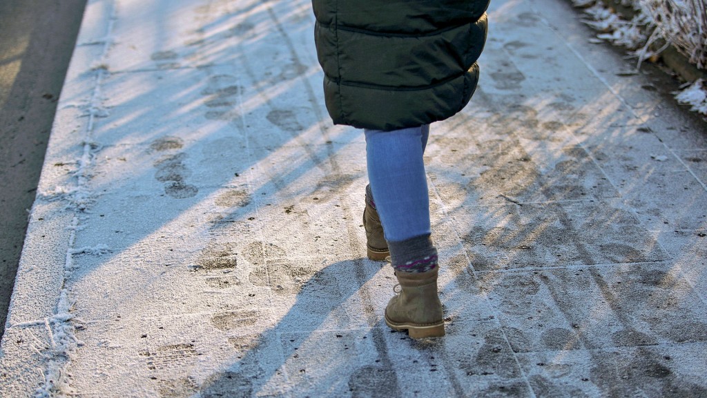 Eine Fußgängerin geht über dünnen Puderschnee