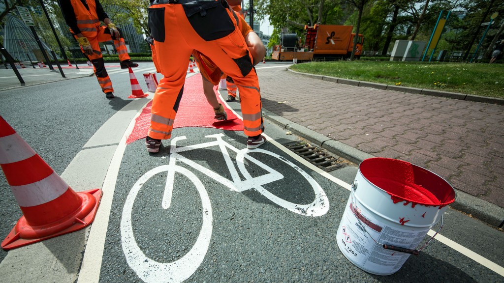 Foto: Arbeiter streichen rote Signalfarbe auf einem Radweg aus