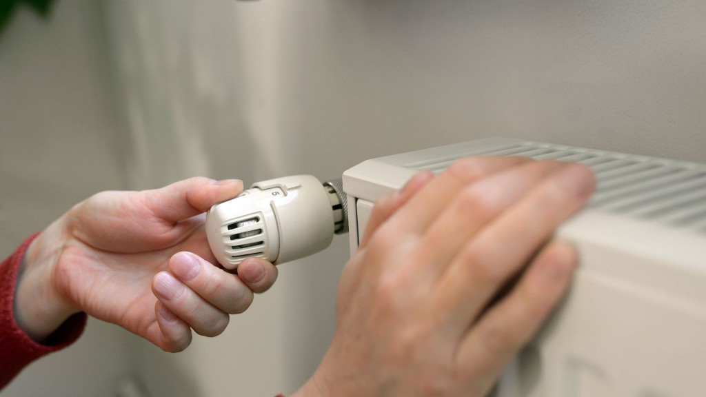 Foto: Jemand fasst an einen Heizkörper und den Thermostatregler