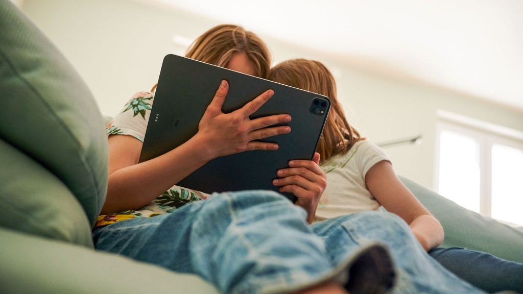 Zwei Kinder sitzen mit einem Tablet auf der Couch