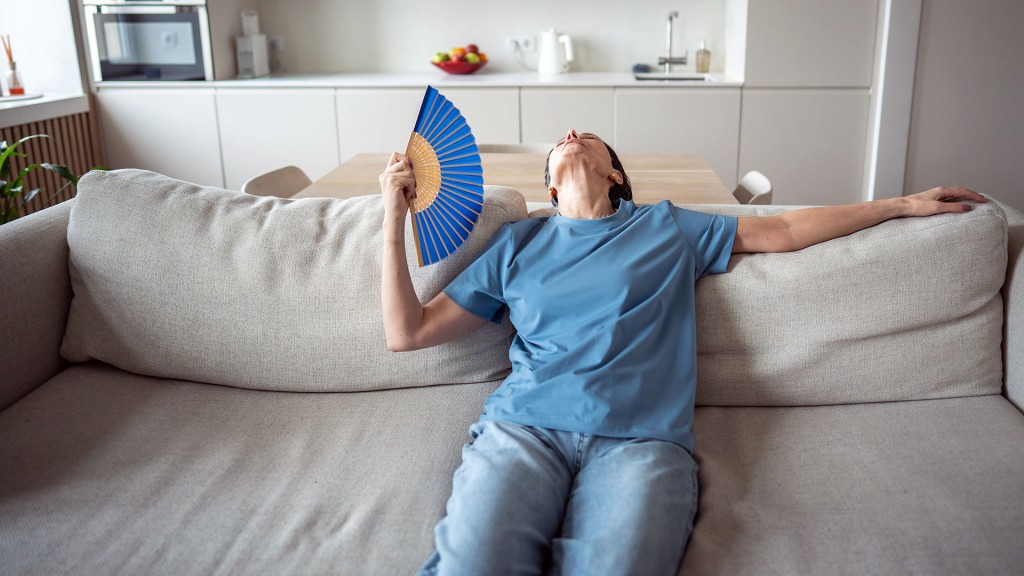 Eine Frau mittleren Alters wedelt sich Luft mit einem Fächer zu
