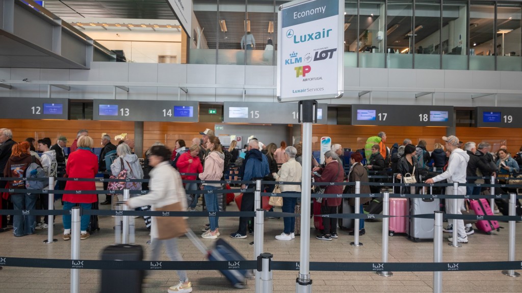 Passagiere stehen mit ihrem Gepäck an einem Abflugschalter des Luxemburger Flughafens Findel. 
