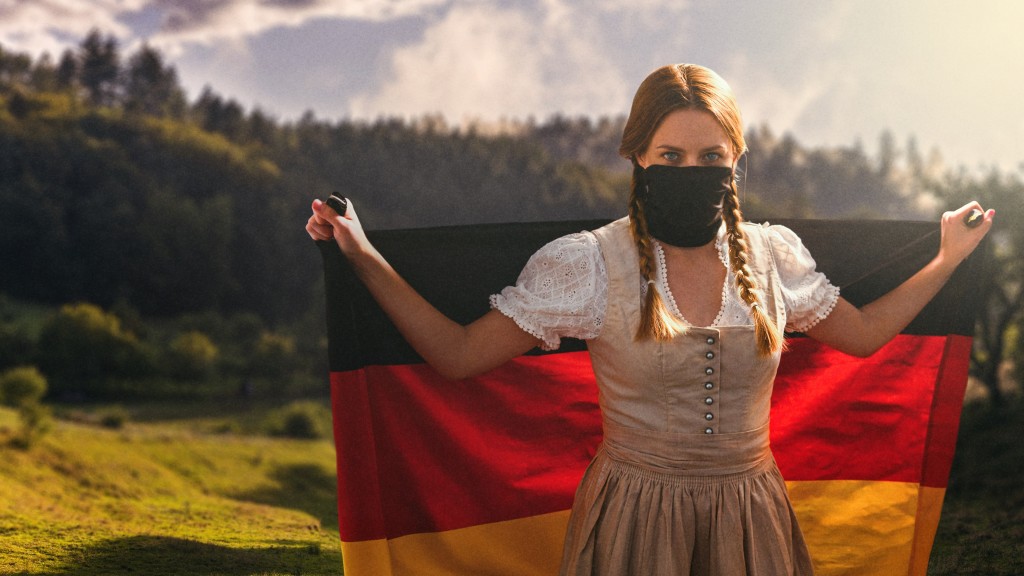 Eine Frau in Tracht steht vor einer Gebirgskette. Der Himmel ist in warmen Farbtönen dargestellt. Die Frau hält eine ausgebreitete schwarz-rot-goldene Deutschland-Fahne hinter sich. Ihr Mund ist mit einem schwarzen Tuch verdeckt. Sie trägt zwei gefloch