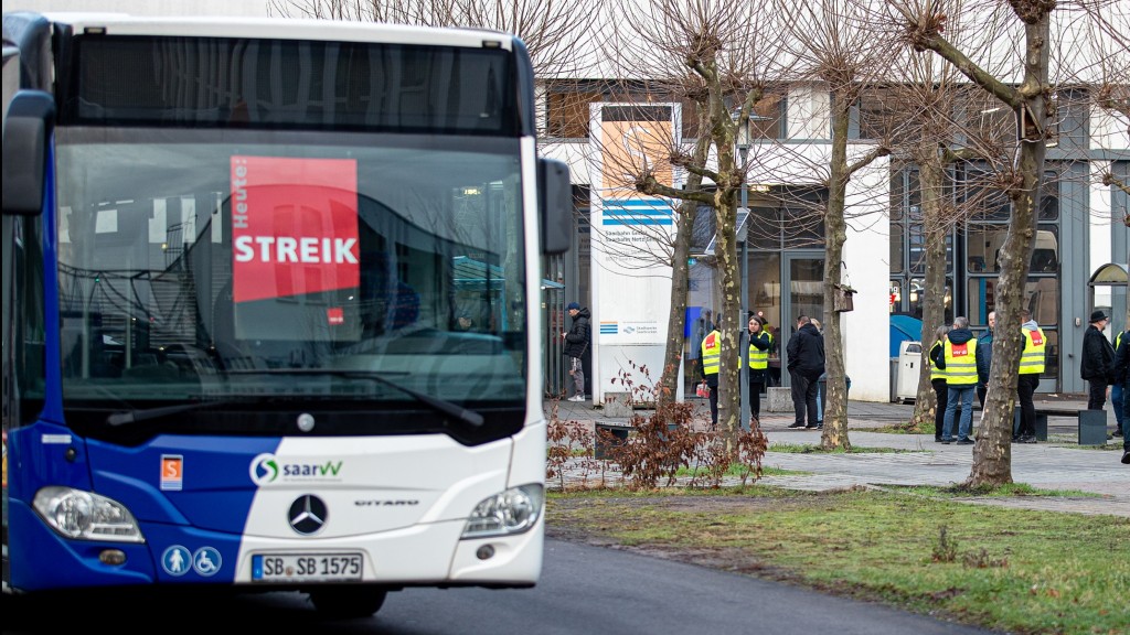 Bus mit Streikplakaten in der Windschutzscheibe und Busfahrer mit gelben Westen im Hintergrund.