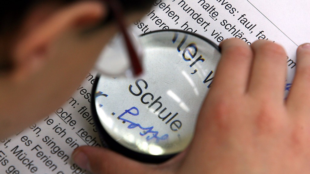 Ein sehbehinderter Schüler liest mit Hilfe einer Lupe