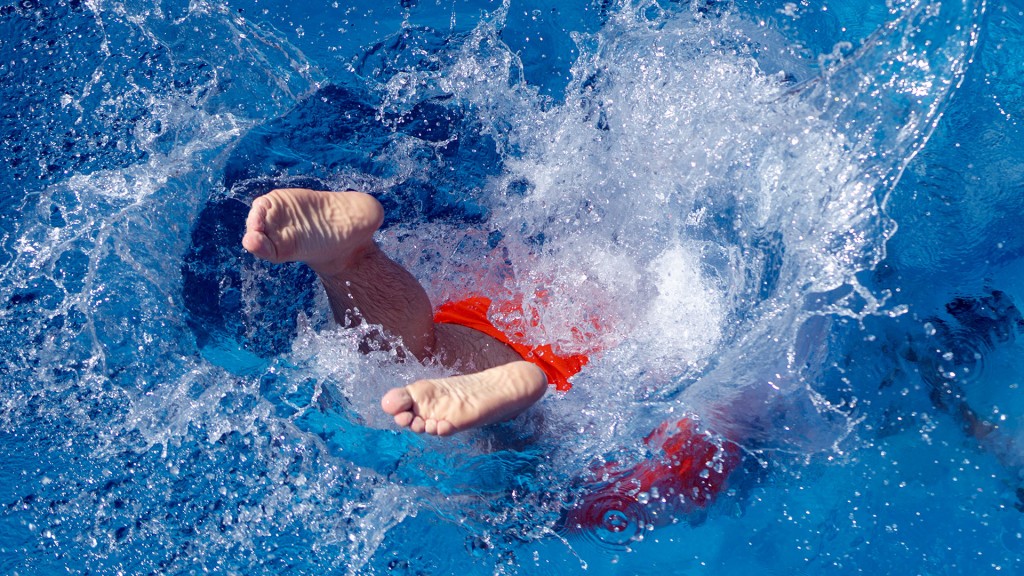 Ein Badegast springt ins Schwimmbadwasser