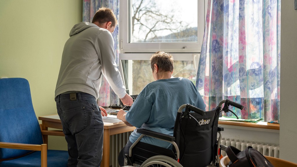 Foto: Eine Rollstuhlfahrerin und ein junger Mann in einem Patientenzimmer