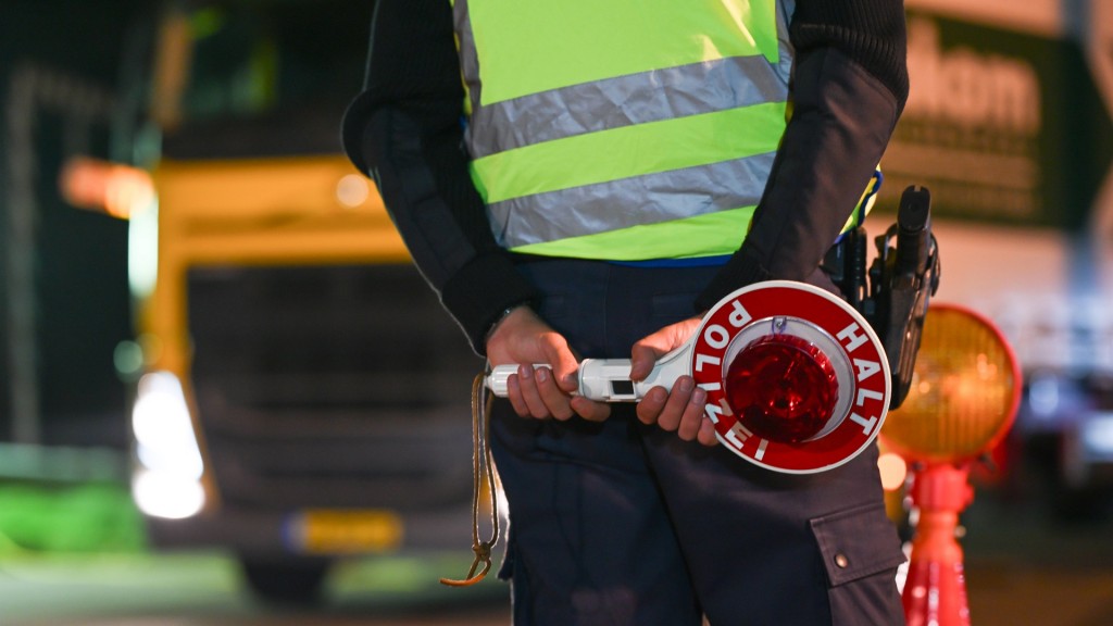 Foto: Polizisten kontrollieren den Grenzverkehr. Ein Polizist mit einer Polizeikelle.