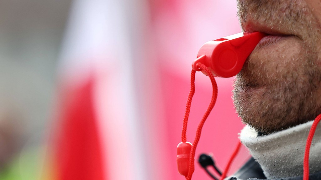 Foto: Mann mit roter Trillerpfeife im Mund