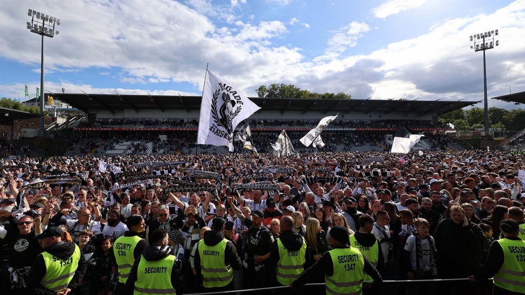 Foto. Fans der SV Elversberg feiern den Aufstieg auf dem Rasen