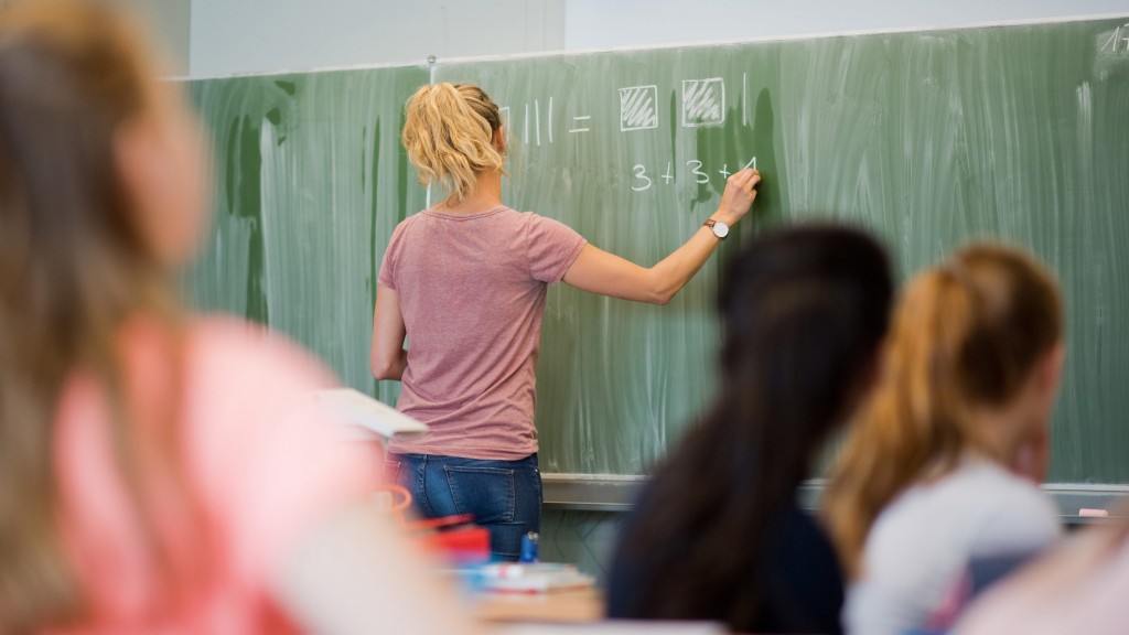 Foto: Eine junge Grundschullehrerin schreibt etwas an die Tafel