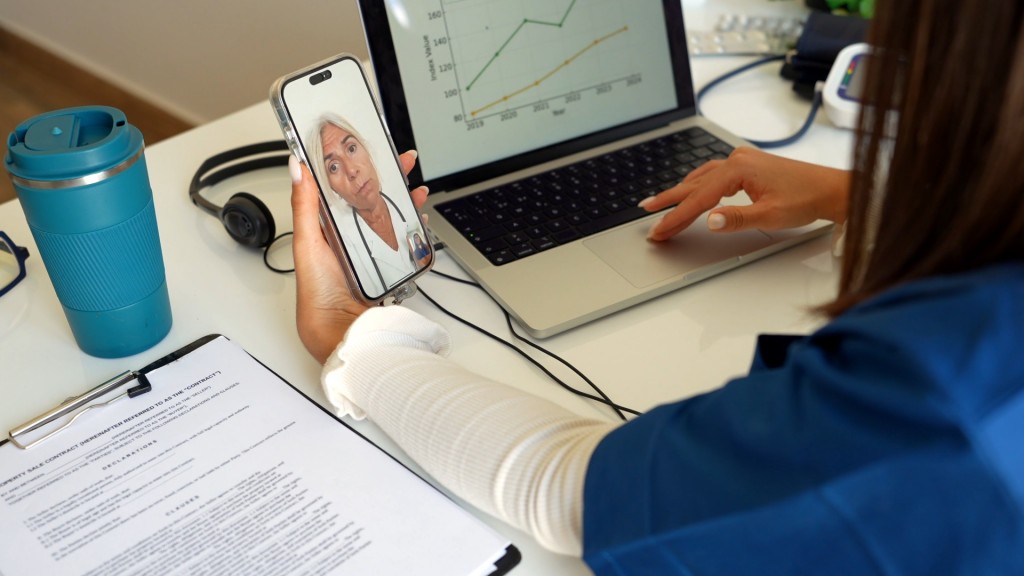 Foto: Eine Frau sitzt an einem Schreibtisch mit Laptop. Sie macht gerade einen Videoanruf