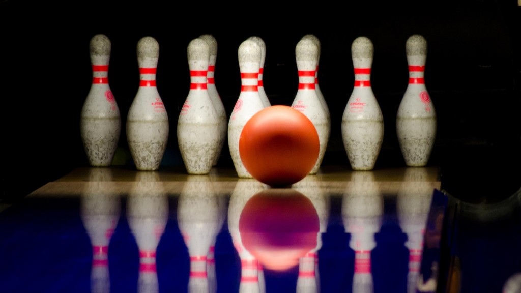 Auf Bowlingpins rollt eine orangene Bowlingkugel zu