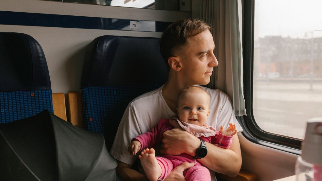 Foto: Ein Mann sitzt mit Baby auf dem Arm im Zug