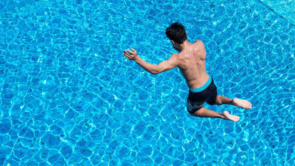Mann springt von Turm in Schwimmbecken