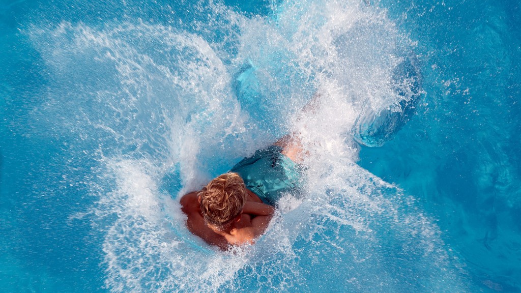 Ein Junge springt im Freibad ins Wasser