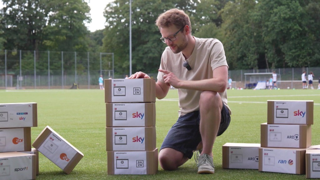 Foto: Mann mit Paketen auf Fußballplatz.