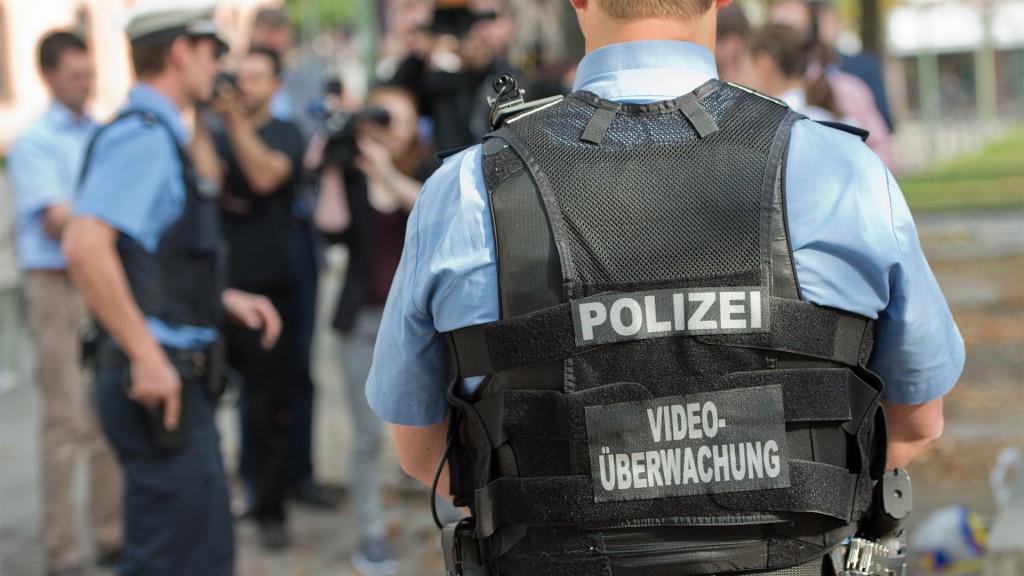Ein Polizist trägt eine Schutztweste mit der Hinweis 