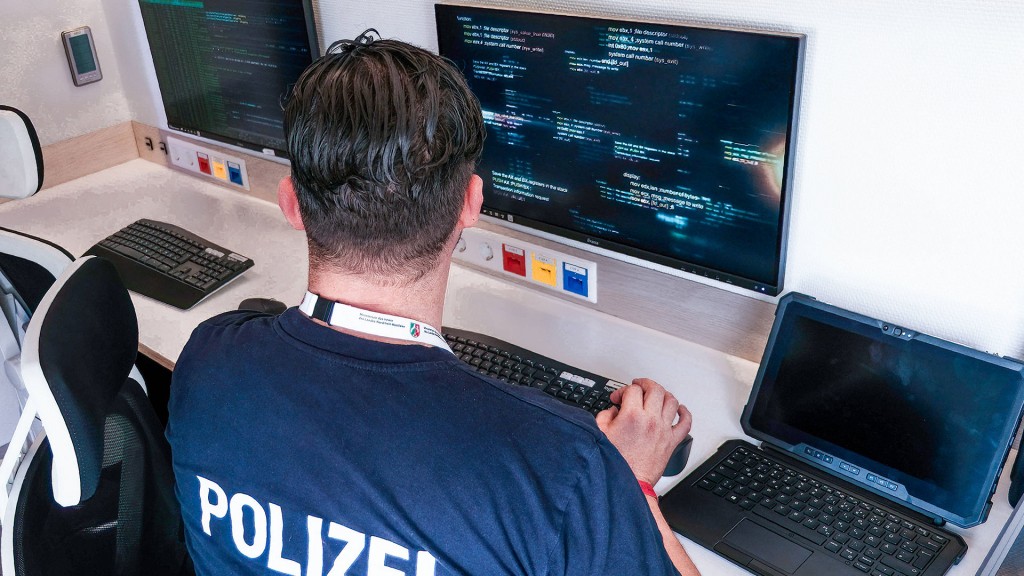 Foto: Ein Polizist sitzt vor Computerbildschirmen